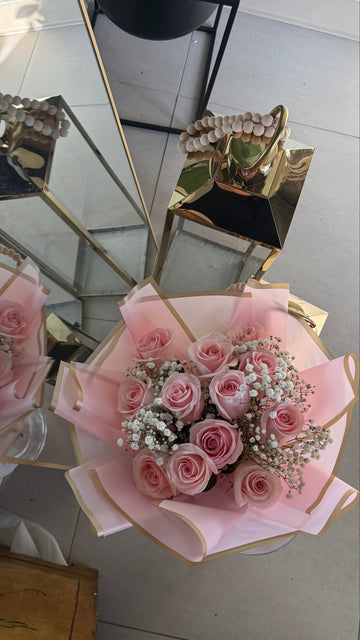 Two bouquets of pink flowers wrapped in cellophane with a decorative bow, placed on a reflective surface.