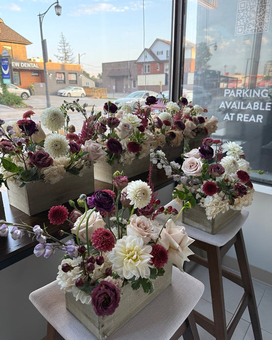 Several coordinated wooden-box floral centrepieces on display