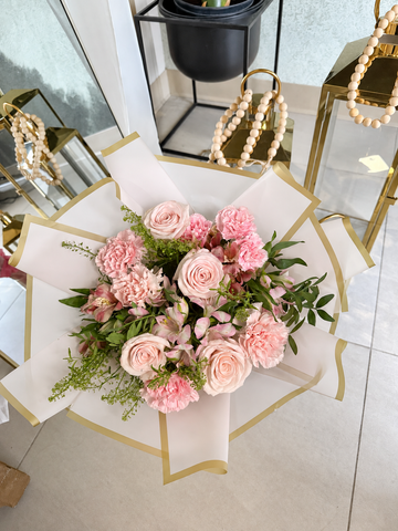 Blush Reverie pink hand-tied bouquet wrapped in white and gold paper